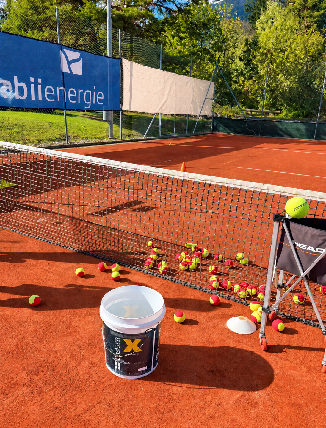 Sandplatz mit Tennisnetz, Kinder-Tennisbällen und Trainingsmaterial